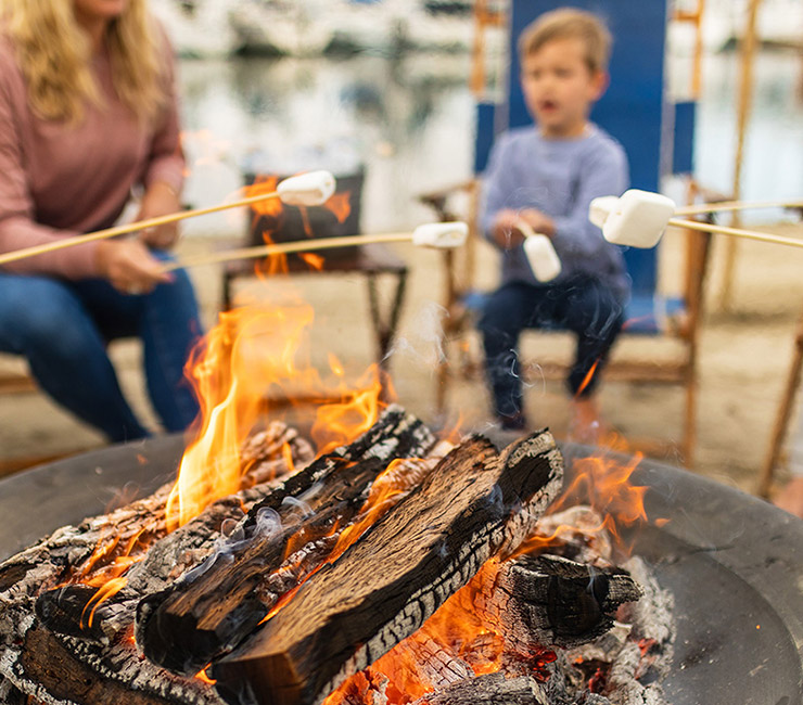 A family enjoying a bayside bonfire and roasting marshmallows steps away from Bahia Beach and Boat Club on Mission Bay, San Diego